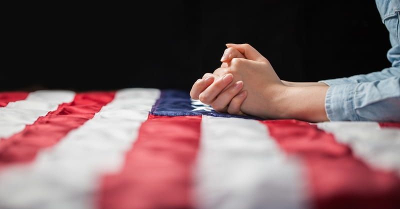 Hands Praying Over American Flag Catholic Focus
